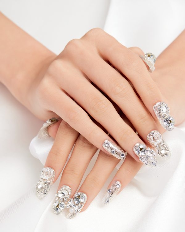 A vertical shot of a female's hands with diamonds on the nails