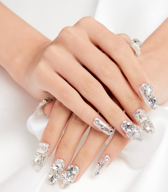 A vertical shot of a female's hands with diamonds on the nails